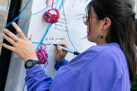 Mujer escribiendo en pizarron sobre la lucha de las mujeres